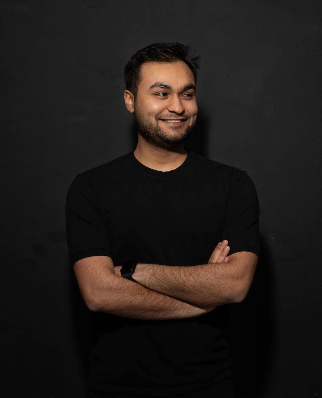 Anand standing on a table with his MacBook in his hand at an office